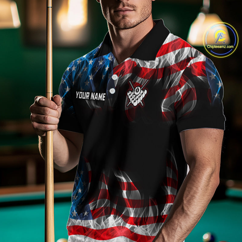 A man holding a pool cue wears a black polo shirt with a red, white, and blue American flag design. The shirt features a customizable name placeholder on the left chest and a crossed-checkerboard graphic with a pool cue on the right chest.