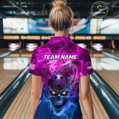 A woman viewed from behind wearing a short-sleeve bowling shirt with a vivid purple, pink, and blue skull-and-smoke graphic on the back, standing in a bowling alley. The shirt has 'TEAM NAME' printed across the upper back, small American flag patches on the sleeves