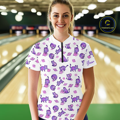 Woman wearing a white shirt with purple cat pattern in a bowling alley.