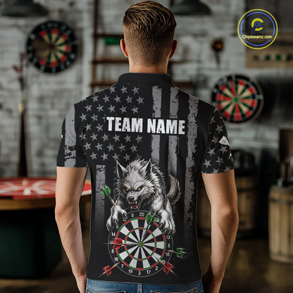 A man viewed from behind wearing a black short-sleeve polo shirt with a large wolf graphic over a dartboard and American flag design, with the text 'TEAM NAME' printed across the back. The shirt is shown in a rustic indoor setting with dartboards in the background.