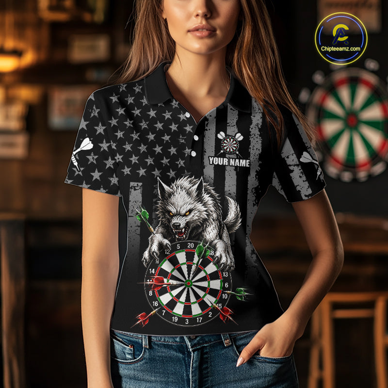 A woman wearing a black short-sleeve polo shirt with a custom graphic print of a snarling wolf扑ing at a dartboard, set against a blurred indoor background with dartboards on the wall.