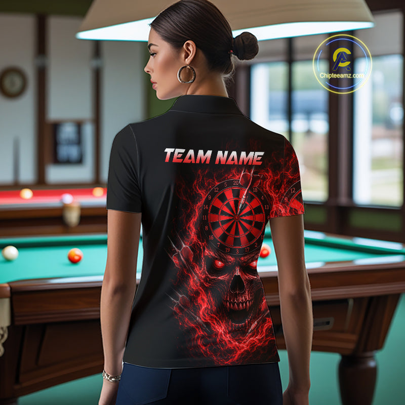 A woman stands in a billiards room wearing a black short-sleeve polo shirt with a red and black skull and dartboard graphic on the back, with 'TEAM NAME' printed above it. A pool table is visible in the background.