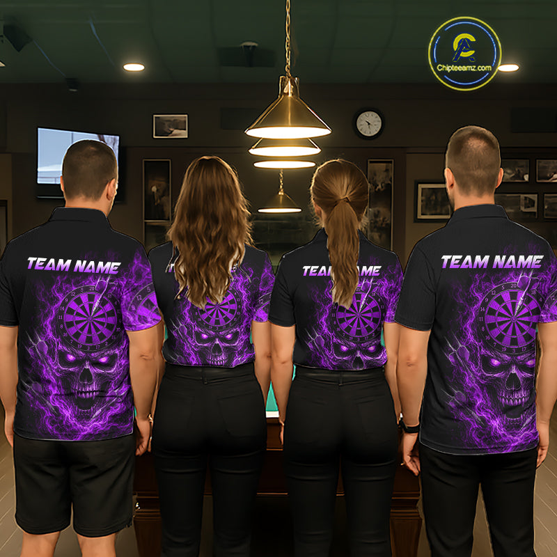 Four people standing with their backs to the camera in a dimly lit indoor room, wearing matching black short-sleeve shirts with a large purple skull and dartboard graphic on the back, plus 'TEAM NAME' text across the shoulders.