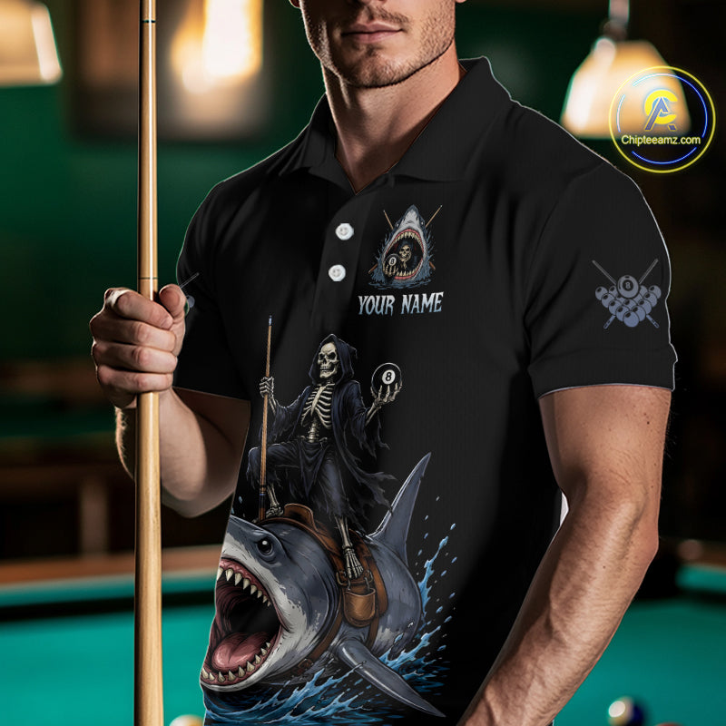 Man wearing a black polo shirt with a shark and skeleton design, holding a pool cue in a billiards setting.