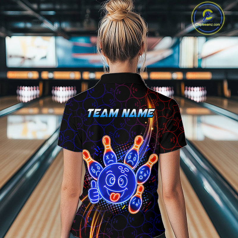 Woman standing in a bowling alley wearing a black neon-style bowling quarter zip shirt with a glowing blue cartoon bowling ball mascot, fiery orange pin graphics, and custom team name text.