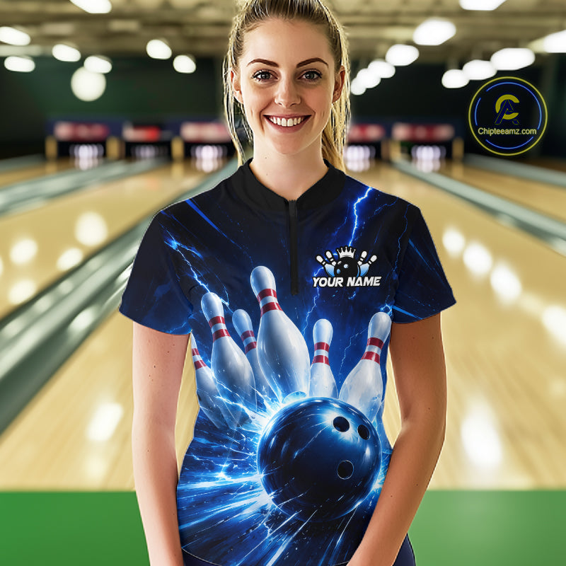 Woman wearing a black and blue bowling quarter zip shirt featuring lightning effects, a large blue bowling ball striking pins, and custom player name text.