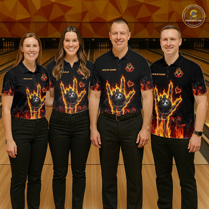 Four people standing in a bowling alley wearing matching black short-sleeve shirts with a fiery flame-ball graphic on the front and black pants.