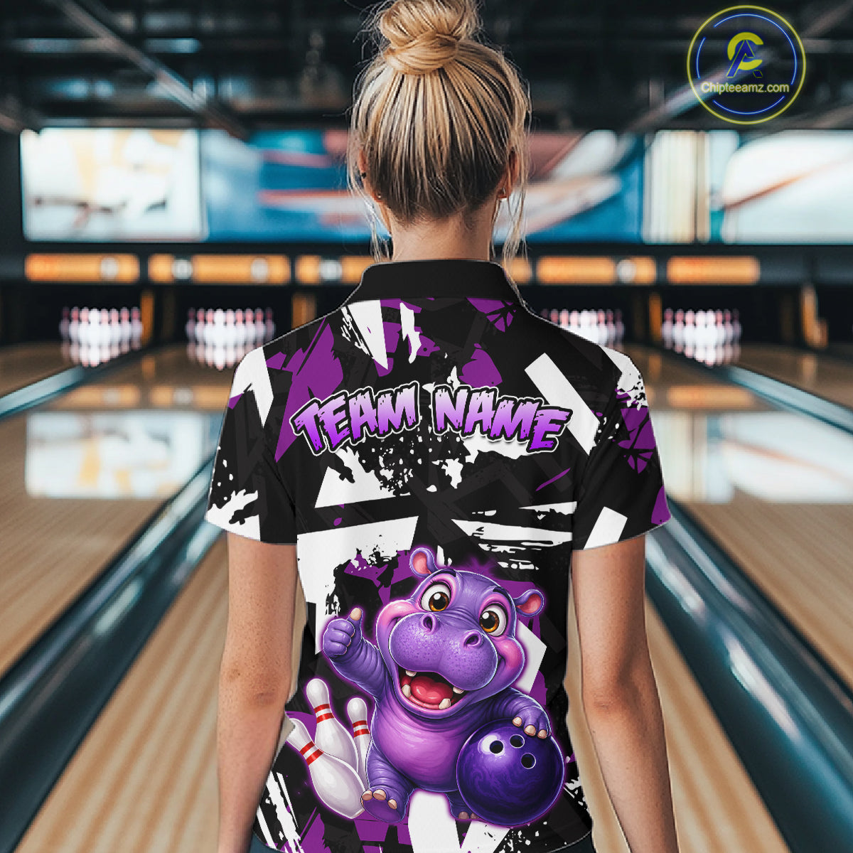Woman wearing of a black, white, and purple bowling polo shirt featuring a cheerful purple hippo holding a bowling ball, with custom player name text.