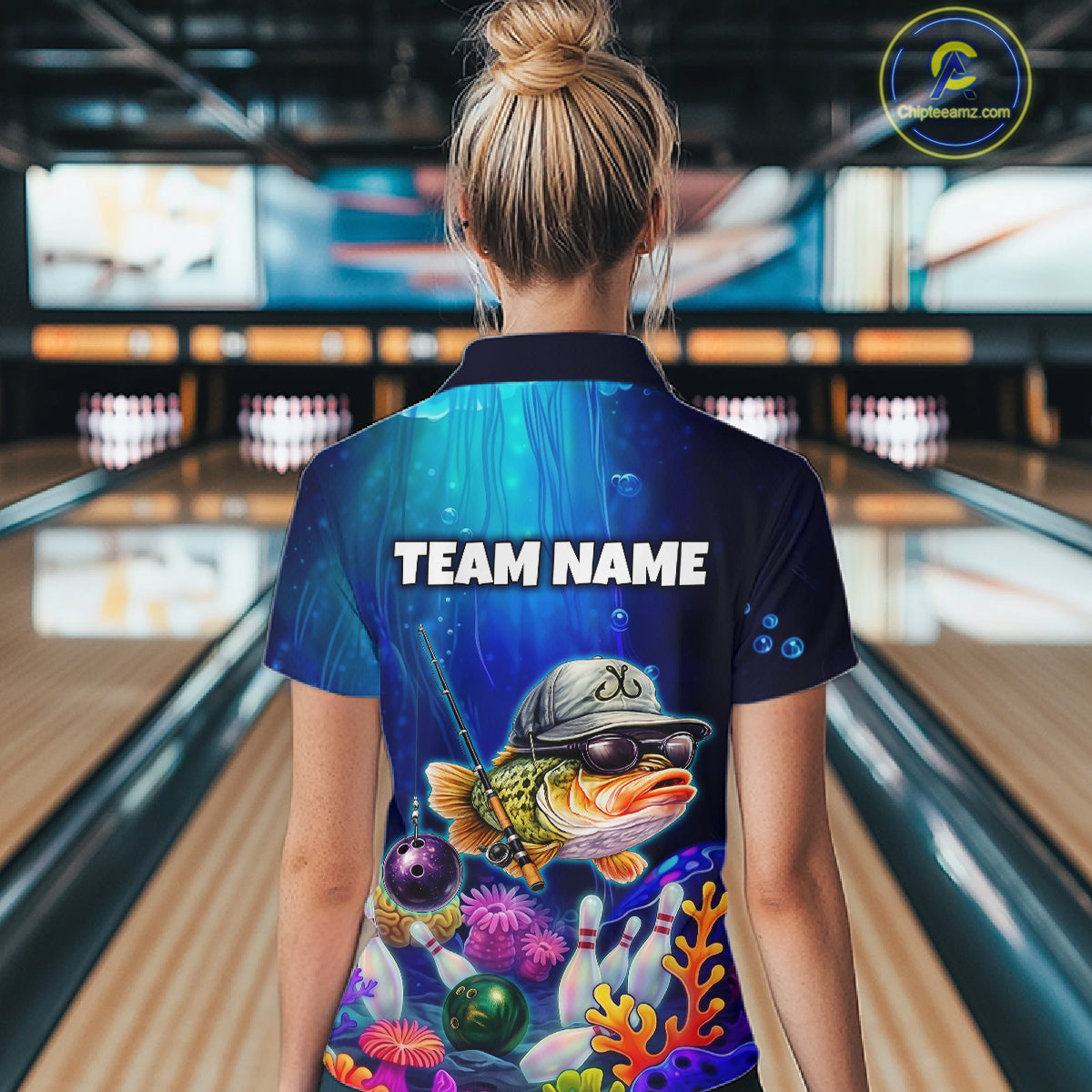 Woman wearing an underwater-themed bowling polo featuring a fish mascot wearing sunglasses and a cap, colorful coral reefs, bowling pins, bowling balls, and custom team text.