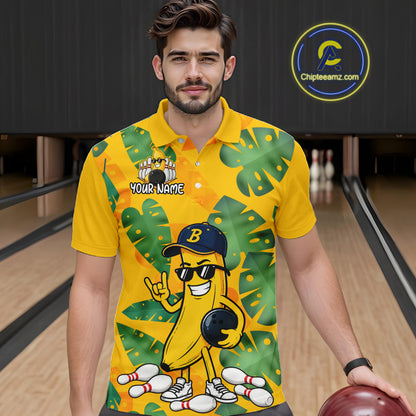 Man in a bowling alley wearing a bright yellow tropical polo shirt with green leaf patterns, custom name text, and a smiling banana mascot holding a bowling ball.