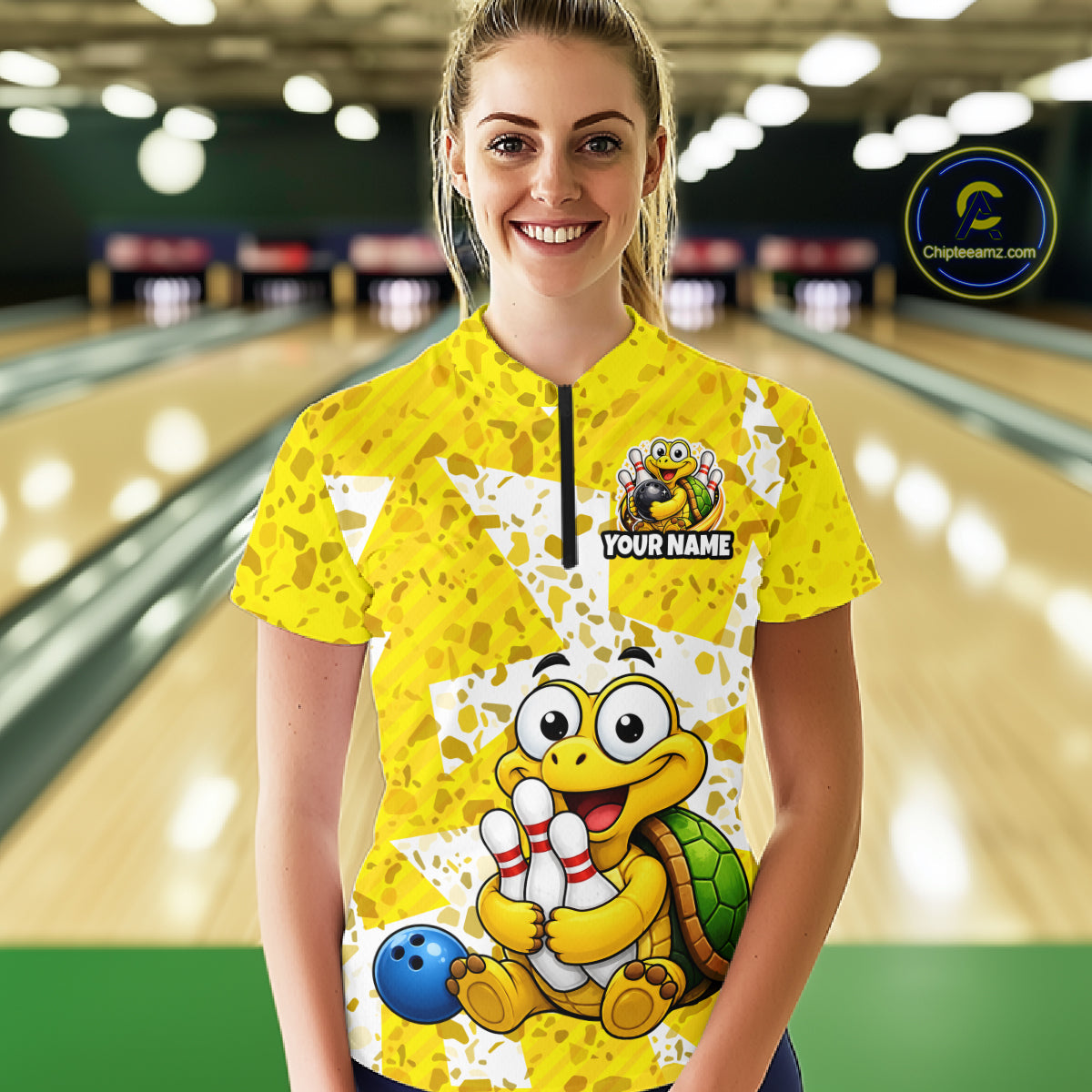 Woman wearing a yellow bowling jersey with cartoon turtle design in a bowling alley.