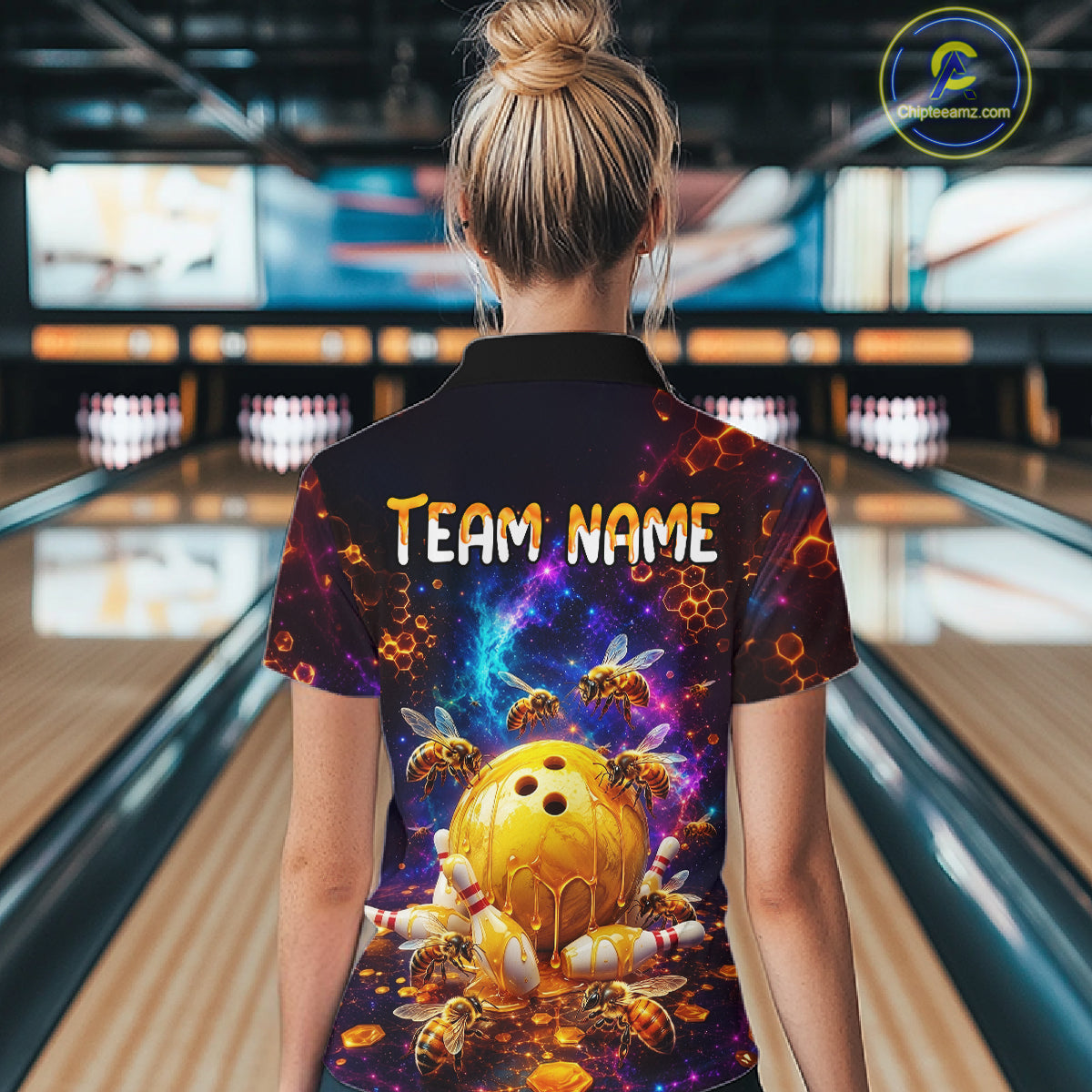 Woman wearing of a dark bowling polo with cosmic honeycomb graphics, bees, honey-dripping bowling balls, pins, and custom team name text.