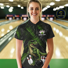 Load image into Gallery viewer, Women wearing bowling quarter zip shirt featuring a dinosaur standing among bowling pins and ball artwork on black green textured background.