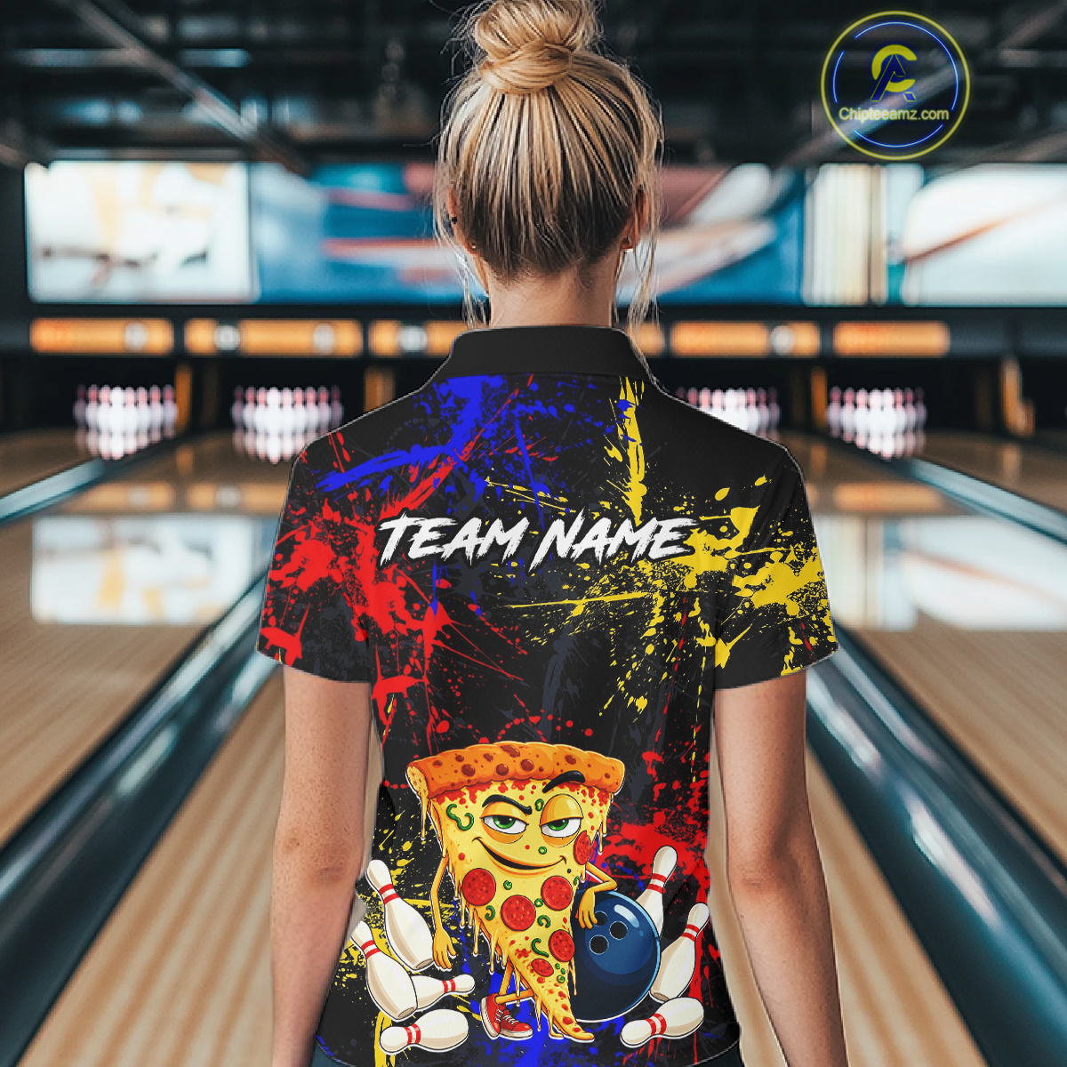 Woman wearing a black bowling polo featuring colorful red, yellow, and blue paint splatter graphics, a cartoon pizza slice mascot, bowling pins, and custom team name text.