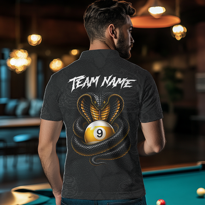 A man viewed from behind wearing a dark gray short-sleeve polo shirt with a large graphic on the back. The design features a black and gold cobra snake wrapping around a yellow 9-ball pool cue, with 'TEAM NAME' printed in white above.