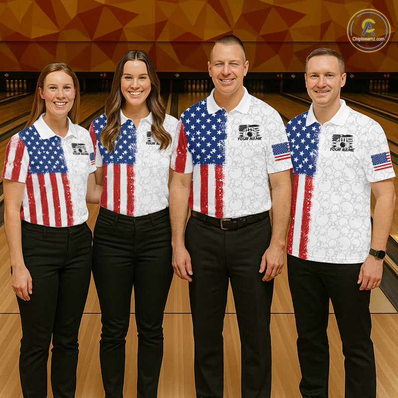 Four people standing together in a bowling alley wearing matching white bowling shirts with an American flag design, paired with black pants. The shirts feature a blue star field on the upper chest and red-and-white vertical stripes below, with a small US flag on the sleeve.