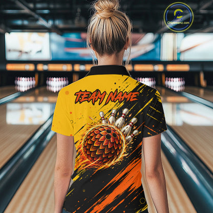 A woman viewed from behind wearing a bowling-themed short-sleeve t-shirt with a dynamic ball graphic and 'TEAM NAME' text, standing in a bowling alley.