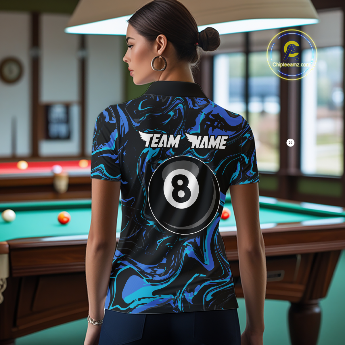 Back view of a woman wearing a black billiards polo with teal and turquoise marble swirls, “TEAM NAME” text, and a large 8-ball graphic.