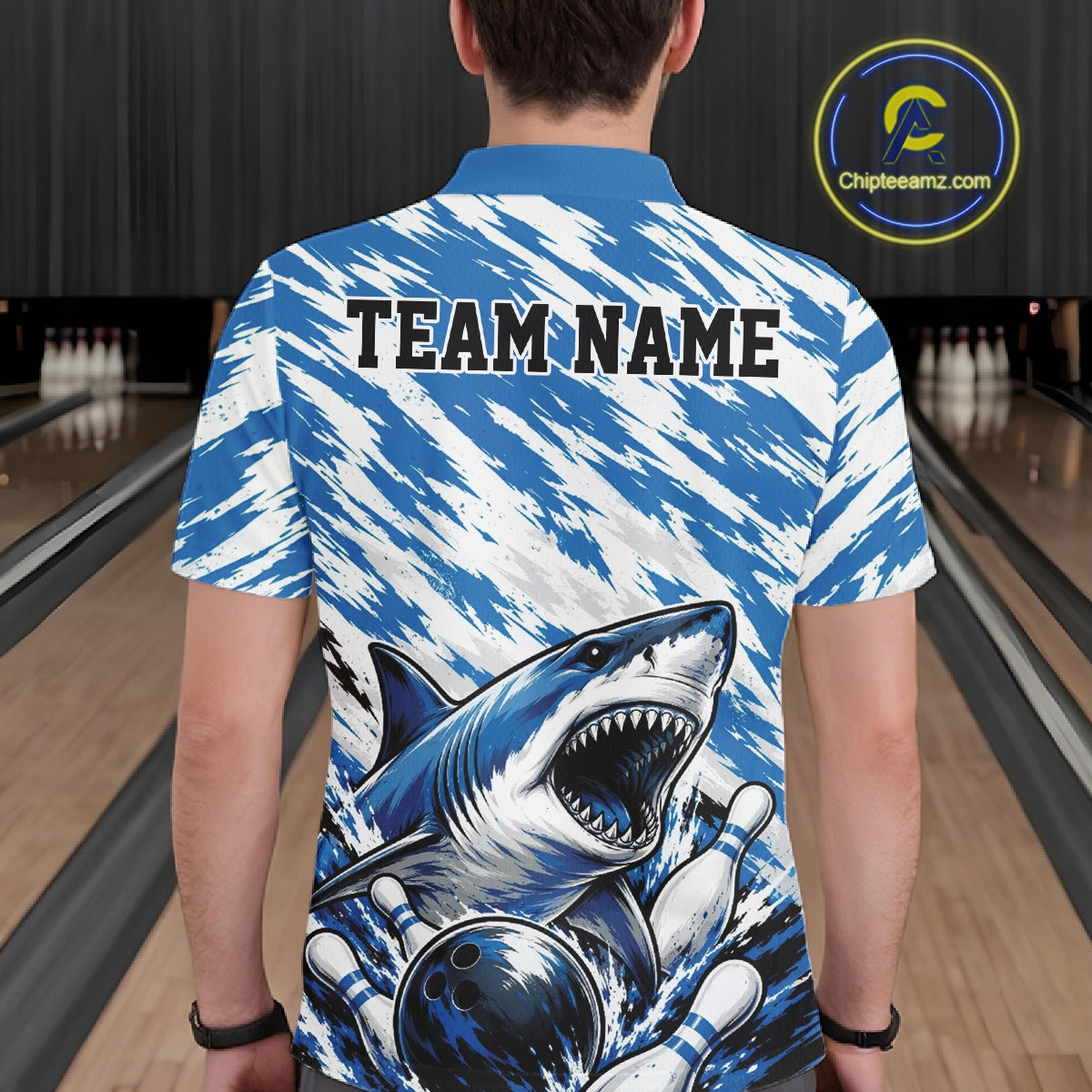 Person wearing a blue and white shirt with a shark design and 'TEAM NAME' text at a bowling alley.