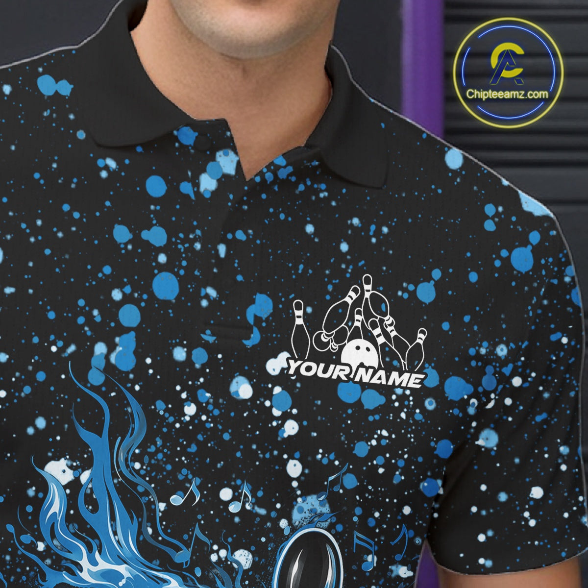 Left chest close-up of a black bowling polo shirt with flaming bowling graphics and blue paint splatter accents.