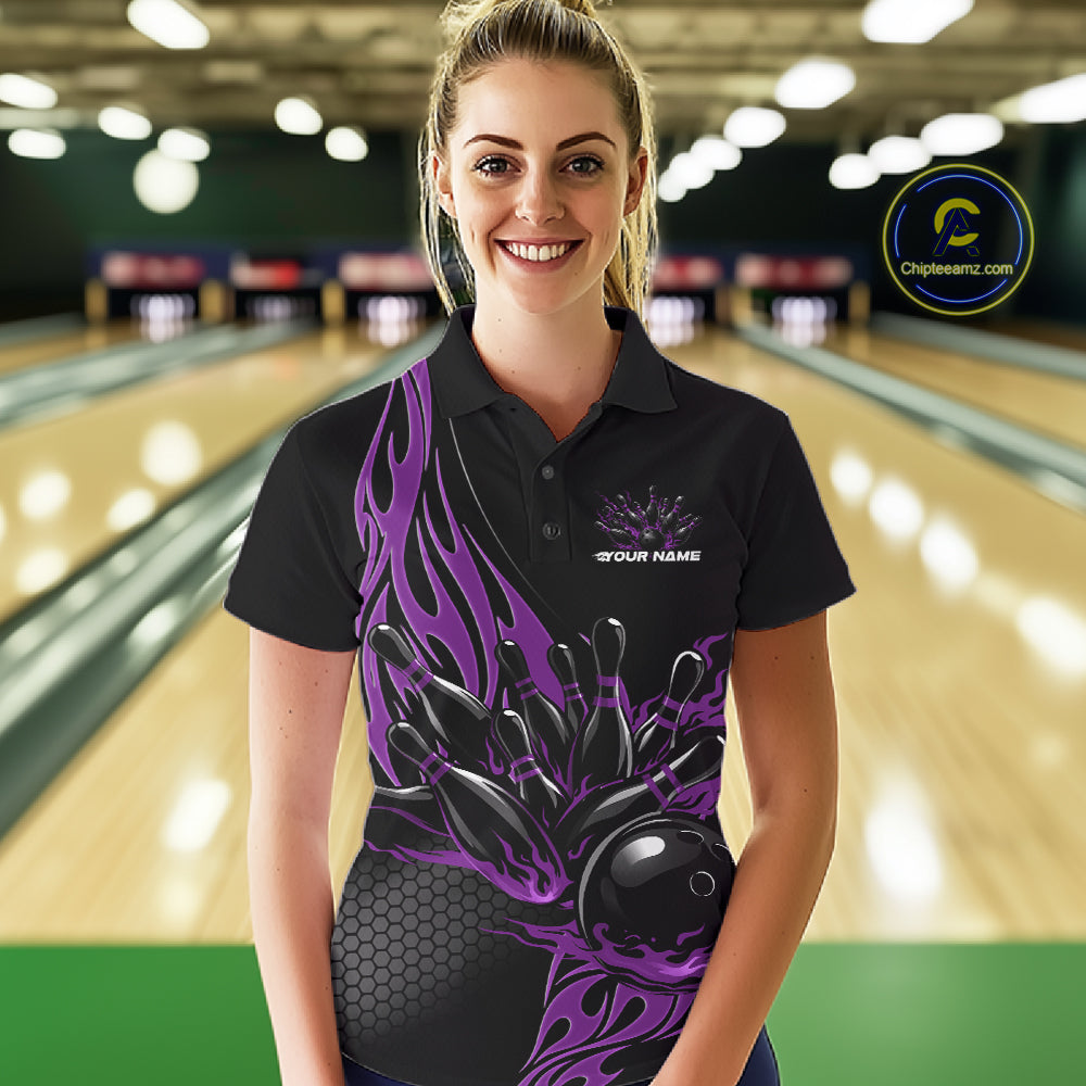Female model front view at a bowling lane wearing a black polo shirt with a purple flaming black bowling ball striking pins in a dynamic action scene.