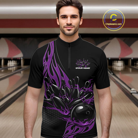 Male model front view in a bowling lane wearing a black quarter zip shirt featuring purple flaming black bowling ball striking pins in a dynamic sports action design.