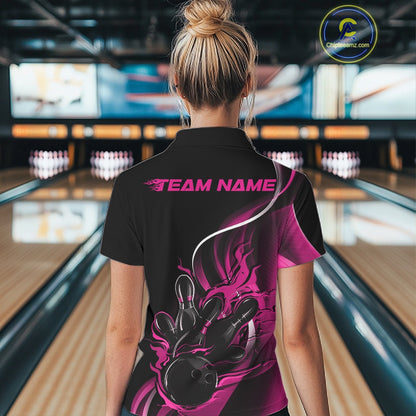 Female model back view in bowling center wearing black and pink polo shirt showcasing flame bowling ball striking pins in vivid motion artwork.
