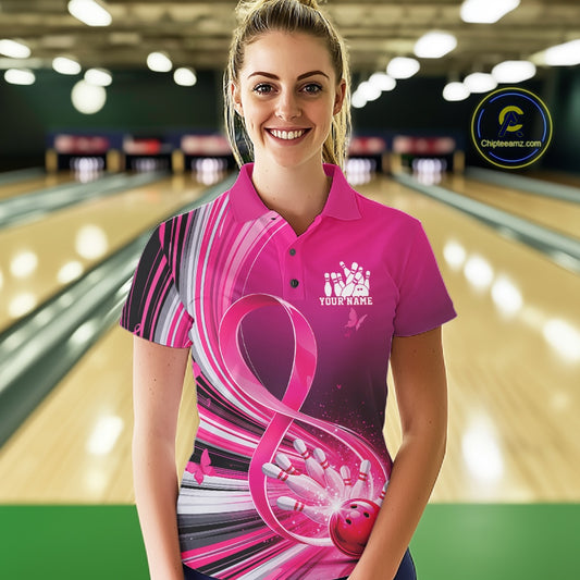 Female model wearing a pink bowling polo with breast cancer awareness ribbon artwork and bowling graphics, front view at the bowling lane