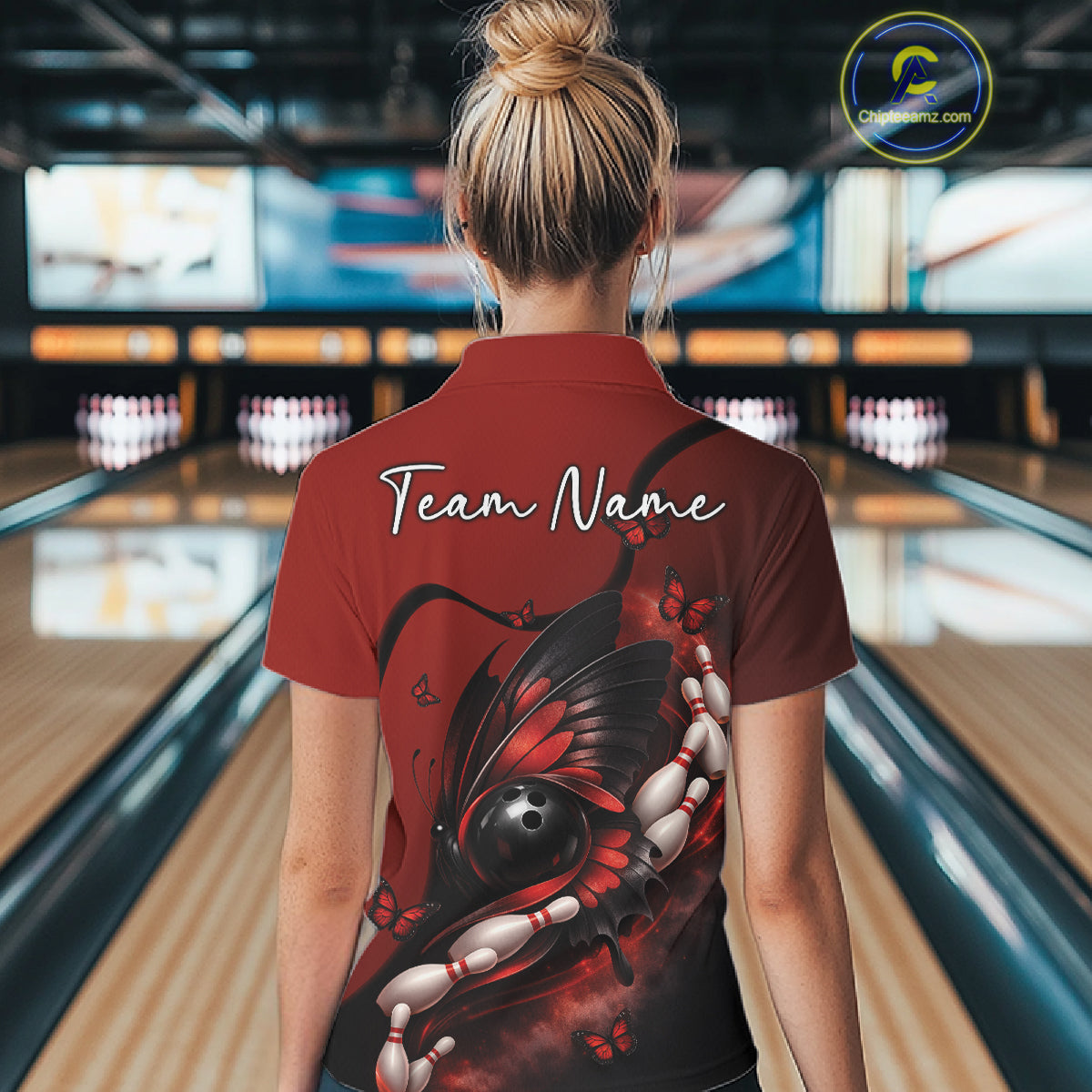 Back view of a female model in a bowling venue wearing a red and black polo shirt featuring a butterfly wrapped around a bowling ball.