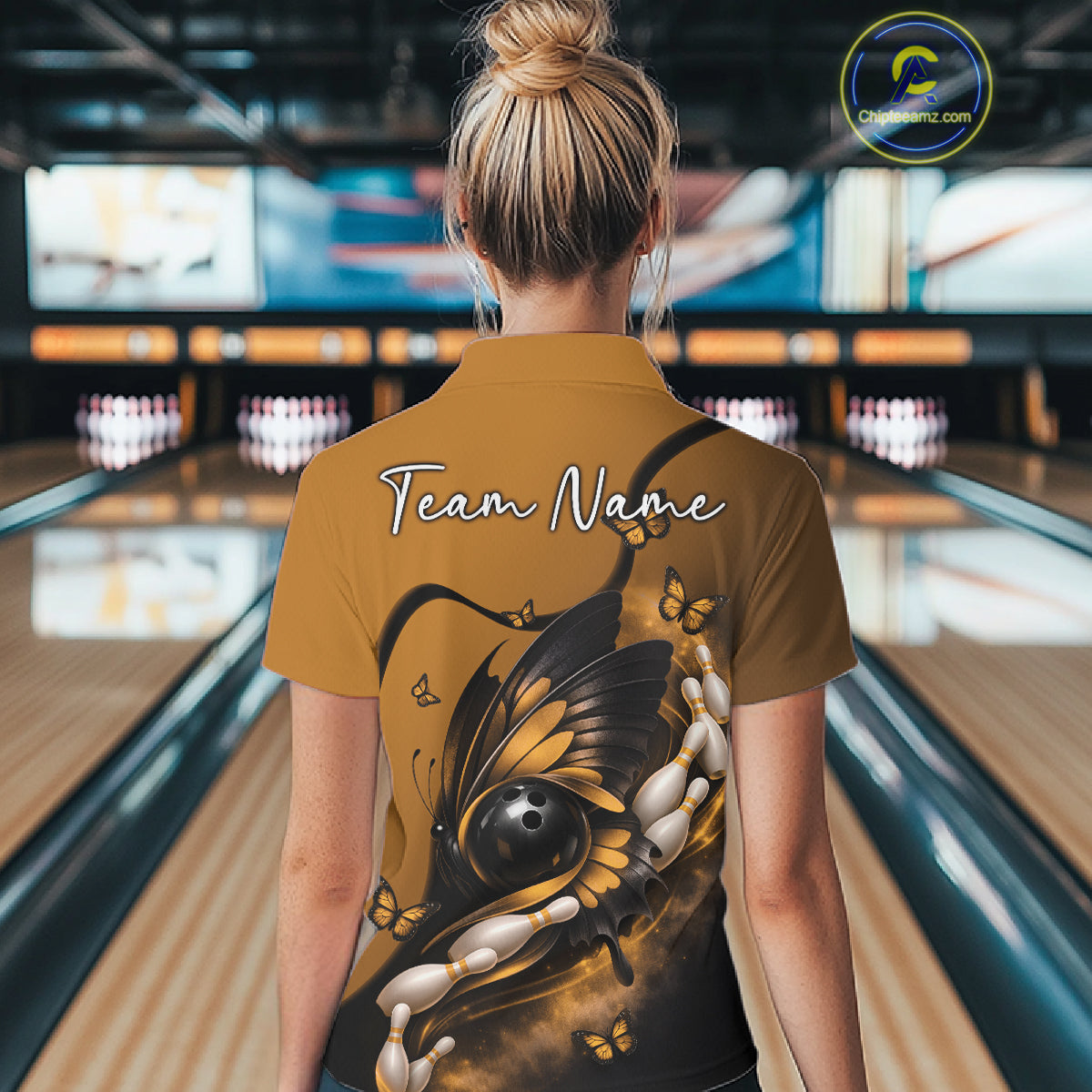 Back view of a female model in a bowling center wearing a yellow and black polo shirt featuring a butterfly wrapped around a bowling ball.
