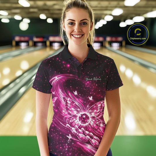 Female model wearing a pink bowling polo shirt in a bowling center with radiant butterfly wings and a bowling ball centerpiece.