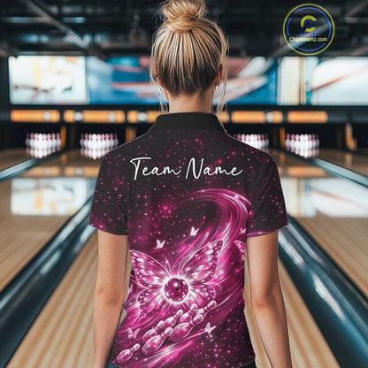 Back view of a female model at a bowling lane wearing a pink polo shirt featuring luminous butterfly wings and galaxy-inspired artwork.