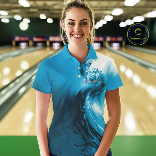 Female model wearing a blue bowling polo shirt with butterfly artwork and bowling graphics inside a bowling alley.