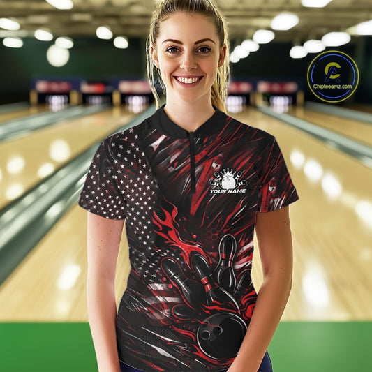 Female model in a bowling lane wearing black and red quarter zip shirt, front view featuring patriotic flaming bowling ball hitting pins dynamic artwork