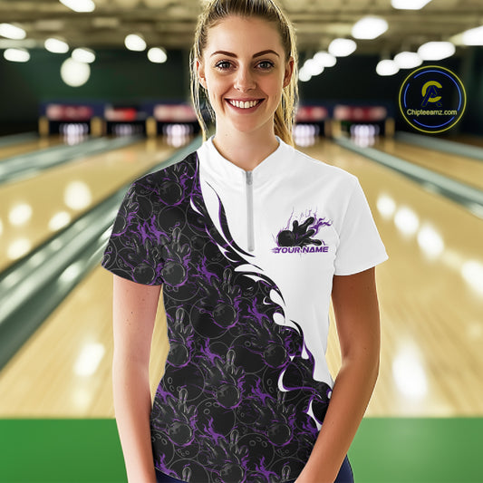 Front view of a female model at a bowling lane wearing a white quarter-zip shirt with purple and black flame bowling pattern and dynamic sports styling.