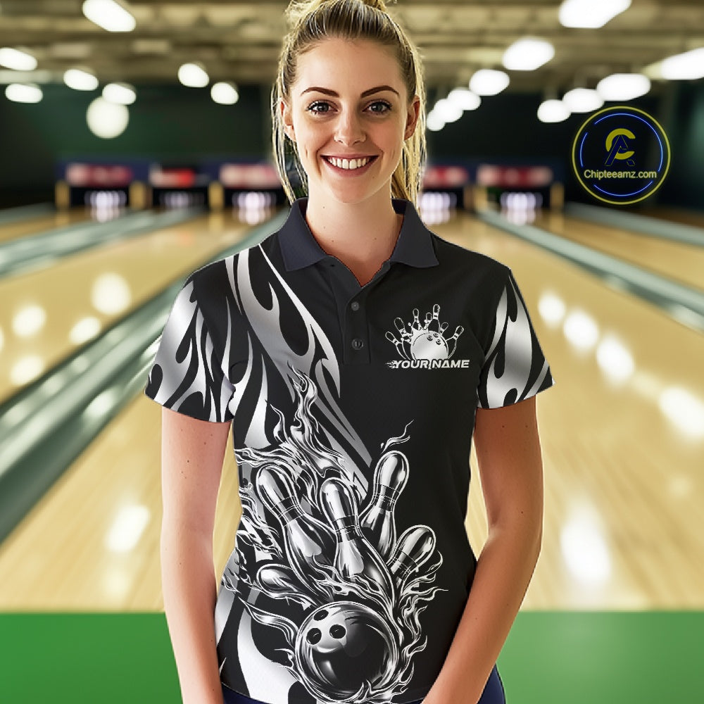 Female model front view in a bowling lane wearing a black polo shirt with a silver metal tribal flame bowling ball striking pins in an intense sports action scene.