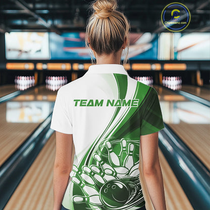 Back view of a female model in a bowling lane wearing a white and green polo shirt, featuring a sweeping bowling ball crashing into pins graphic.