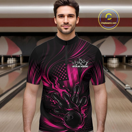 Male model at a bowling lane wearing a black and pink bowling quarter-zip shirt with patriotic bowling strike artwork and fiery flag-inspired details.
