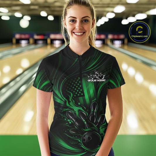Female model at a bowling lane wearing a black and green bowling quarter-zip shirt with patriotic bowling strike artwork and distressed flag graphics.