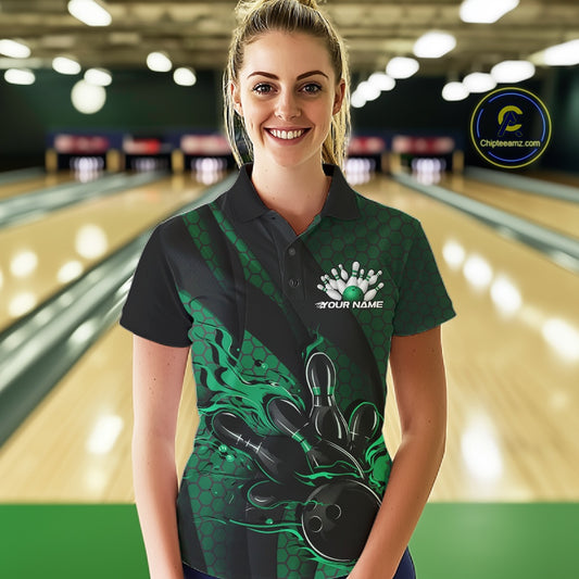 Female model wearing a black and green bowling polo shirt at a bowling lane with fiery bowling action artwork and geometric stripe details.