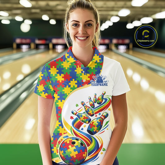 Female model at a bowling lane wearing a white polo shirt, front view showing colorful autism-themed bowling strikes and puzzle graphics