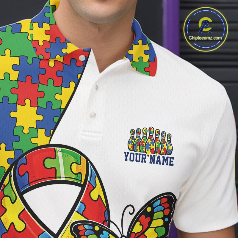 Close-up left chest detail of white bowling polo shirt featuring autism awareness ribbon puzzle emblem with butterfly and bowling strike graphics