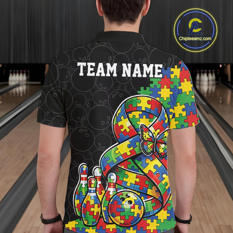 Male model at a bowling lane, back view of black polo shirt showcasing autism awareness ribbon with puzzle fill, butterfly, and bowling ball hitting pins