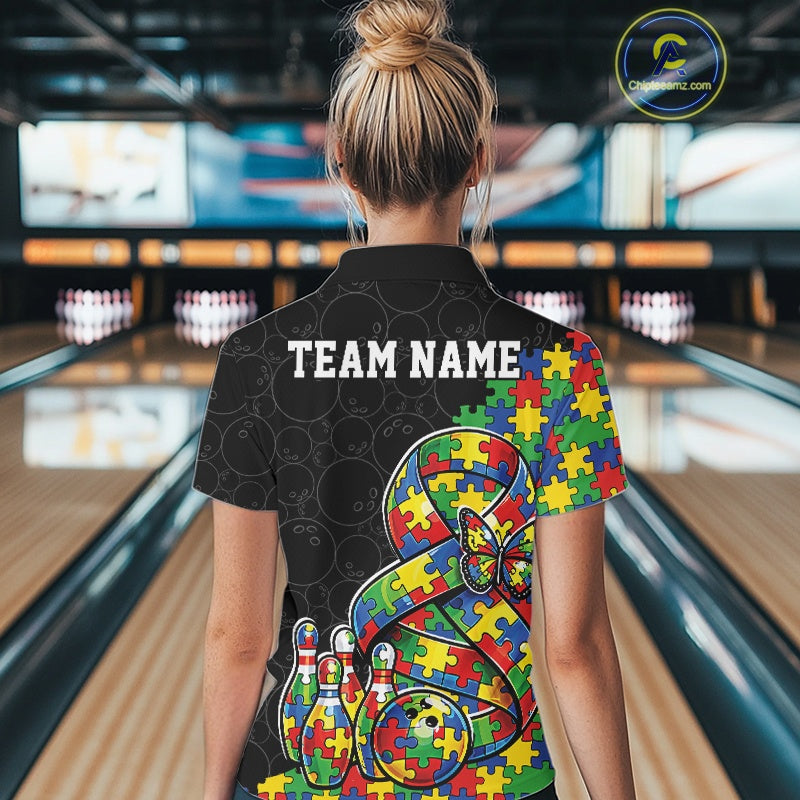 Female model at a bowling lane, back view wearing black polo shirt featuring autism ribbon puzzle design, butterfly detail, and bowling strike scene illustration
