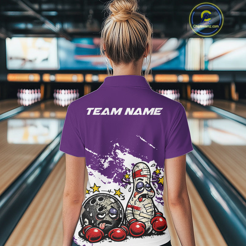 Back view of a female bowler in a purple and white quarter-zip shirt, humorous boxing-themed bowling ball and pin artwork displayed on back.
