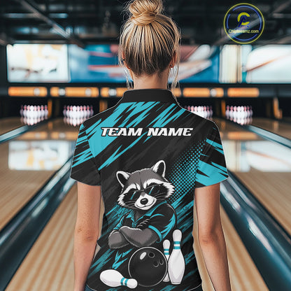 A woman viewed from behind wearing a bowling-themed short-sleeve quarter zip shirt in a bowling alley. The back of the shirt features a raccoon graphic with bowling pins and ball, the text 'TEAM NAME', and a teal and black patterned design.