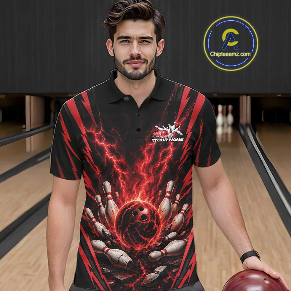 A man wearing a black short-sleeve polo shirt with a red and black lightning-bolt bowling graphic, standing in a bowling alley holding a bowling ball. 