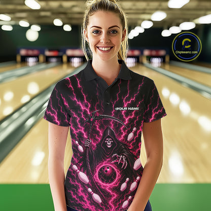 A woman stands in a bowling alley wearing a black short-sleeve polo shirt with a vivid pink and purple grim reaper graphic, bowling pins, and lightning bolts. The shirt features the text 'YOUR NAME' on the left chest.