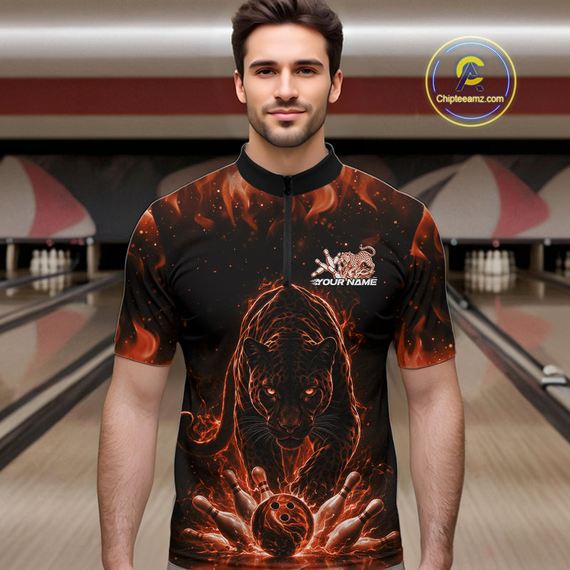 Front view of a male model in a bowling lane wearing a black quarter-zip shirt with glowing orange electric panther and dynamic bowling strike graphics.