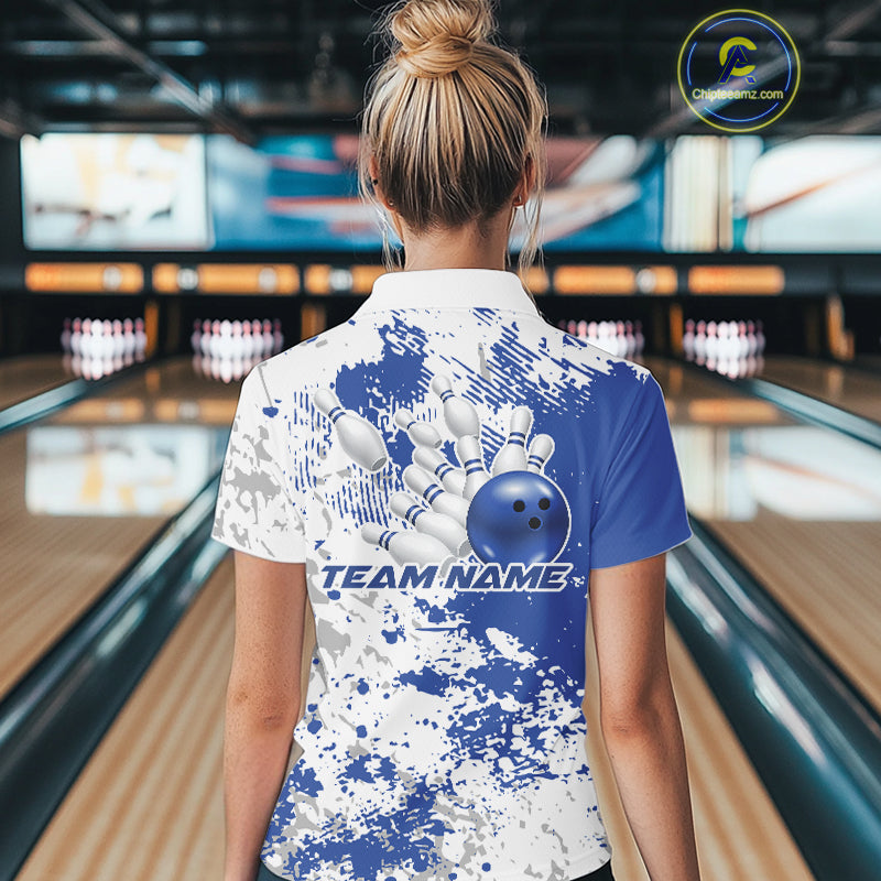 Back view female model in bowling venue wearing white polo with blue and white splatter design, standing near bowling lanes